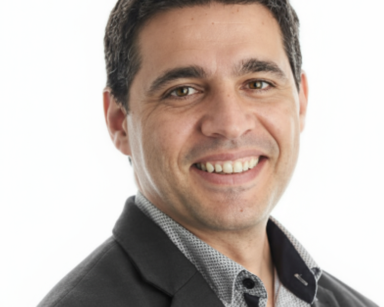 Dr. Adrian Lopresti wearing a dark suit and patterned shirt on a white background